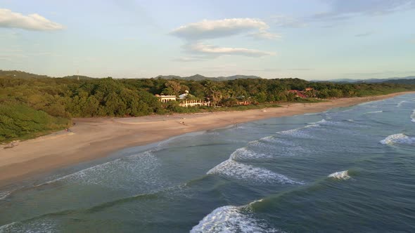 Drone approaching a beachfront hotel at playa grande near Tamarindo, Costa Rica. Few people walk alo