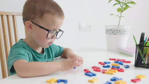 Smart Baby Boy in Glasses Playing Colorful Abc Alphabetic Letters Making Words