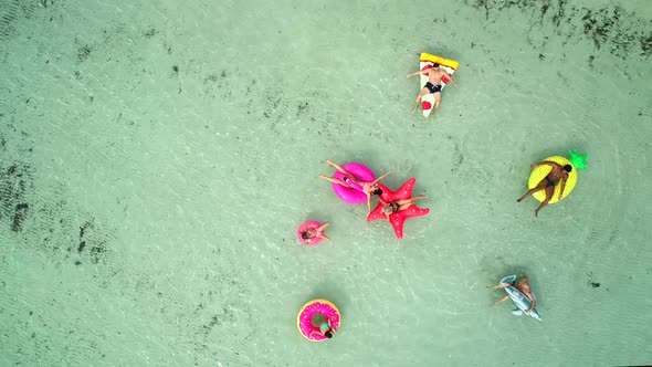 Aerial view of friends floating on inflatable mattresses in transparent sea.