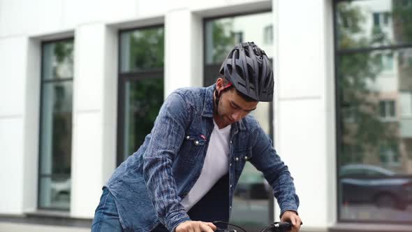 Tracking Shot of Handsome Cyclist Male Stopping on City Street Removing Protective Helmet From Head