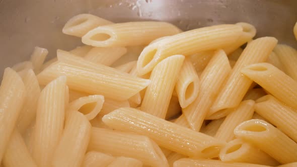 Steaming hot fresh boiled pasta in steel pot in close up view