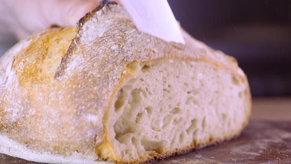 Cutting Homemade Sourdough Bread With Kitchen Knife - close up, pan shot