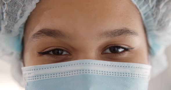 Close Up of African Female Doctor in Mask and Cap Looking at Camera