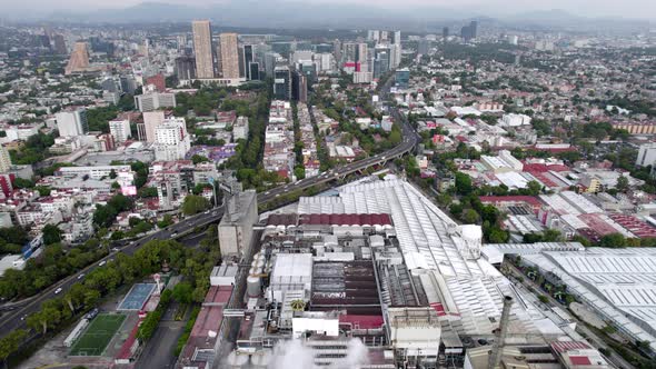 backwards drone shot of beer factory and residential zone at mexico city in the morning