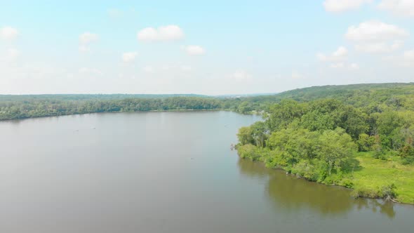 drone flight left over people kayaking on forest lake in a forest preserve of green trees and a blue