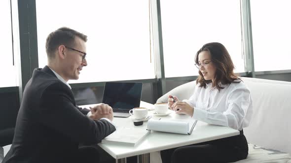 Two Business Partners are Talking Over Cup of Coffee Sitting in Cafe or Restaurant