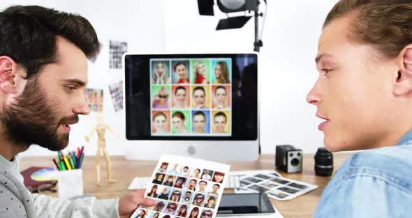 Two photographers having discussion over computer monitor