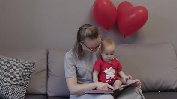 Young Caucasian Mother Glasses Reading Book Baby Child Kid Red Heart Balloons