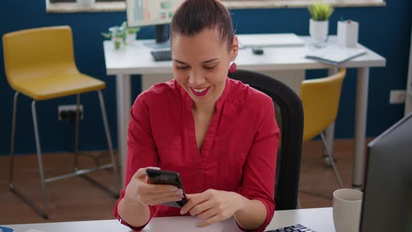 Company Employee Browsing Internet on Smartphone at Desk