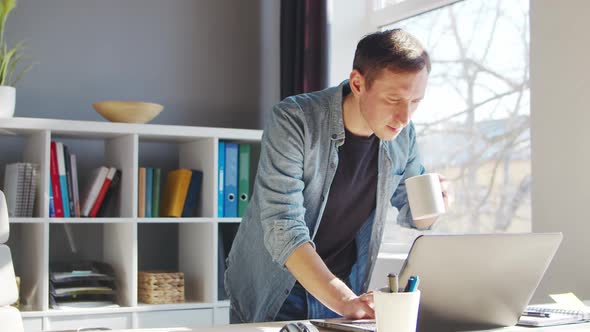 Young male entrepreneur works at home office at the computer.