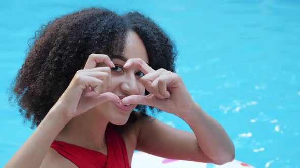 Young African Curly Student Woman on Rest Sitting Near Pool Smiling Friendly Looking at Camera