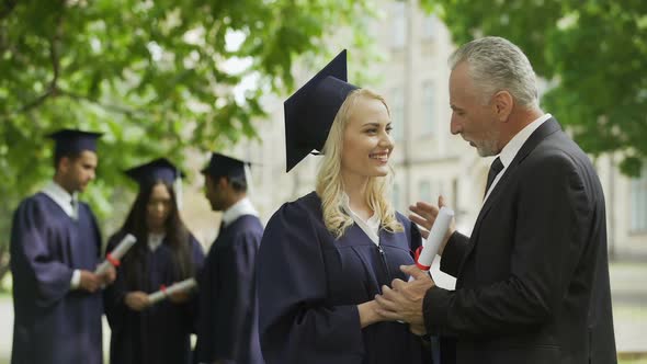 Excited Dad Congratulating Graduate Daughter in Park Near Academy, Happiness