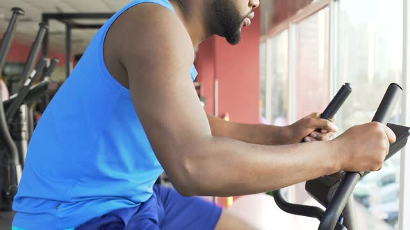 Motivated Man Riding a Stationary Bike, Shaping Up His Body in the Gym