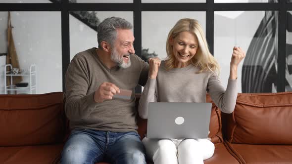 Cheerful Middleaged Couple Using Laptop for Making Purchases in Online Shopping