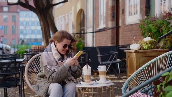 Traveller Woman in Sunglasses Does Does Photos of Her Coffe Cups By Smartphone in the Street Cafe of