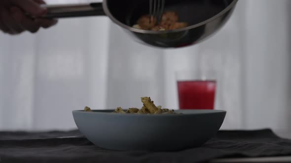 Slow Motion Shrimps Fall Onto Pesto Penne in Bowl