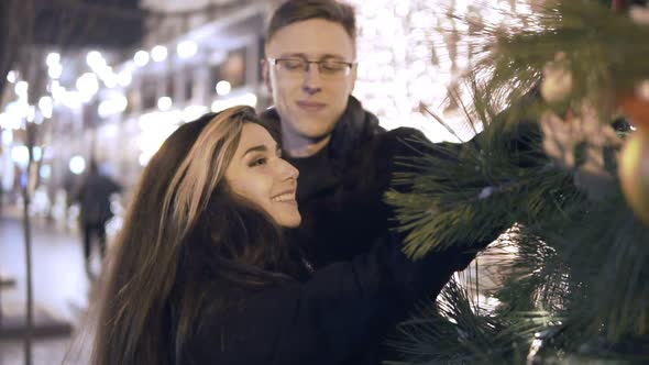 Happy Attractive Couple Standing Near the New Year Tree in a Christmas Market at Night
