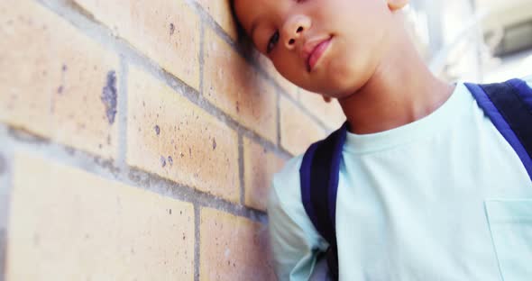 Schoolkid leaning on wall in corridor at school