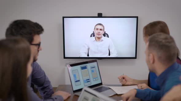 Group of Specialists Are Having Video Conference with Boss in Office Room, Looking at Display