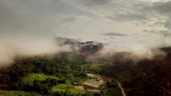 Aerial view flying above lush green tropical rain forest mountain with rain cloud cover during the r