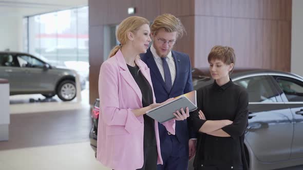 Pleasant Woman in Pink Jacket Showing Information in Book To Customers - Professional Saleswoman