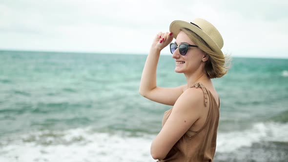 Happy Girl in Hat and Glasses on Ocean Background Slow Motion