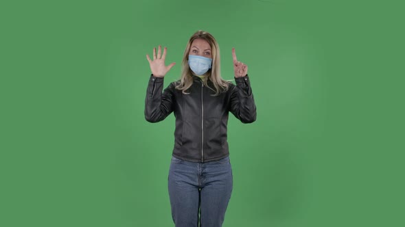 Portrait of Beautiful Young Woman in Medical Protective Face Mask Is Looking at Camera and Shows