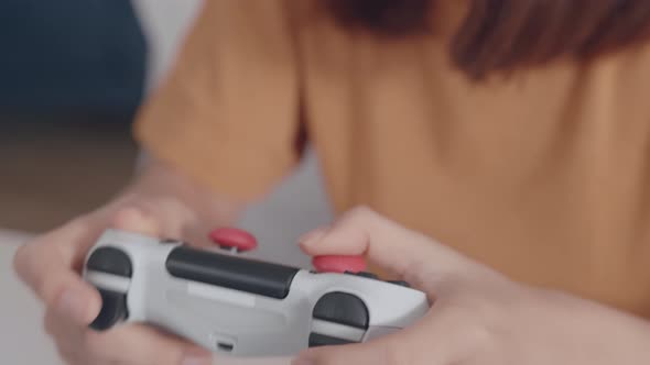 Close up shot of female hand holding white joystick playing a video game