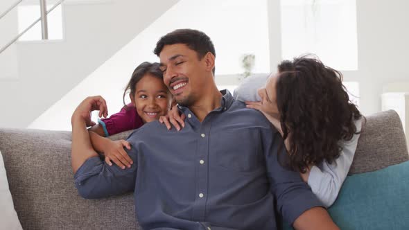 Portrait of happy hispanic parents and daughter embracing in living room