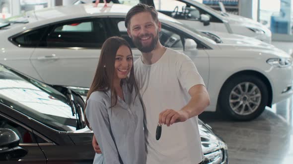 The Concept of Buying or Renting a Car. Young Happy Interracial Couple with New Car Keys.