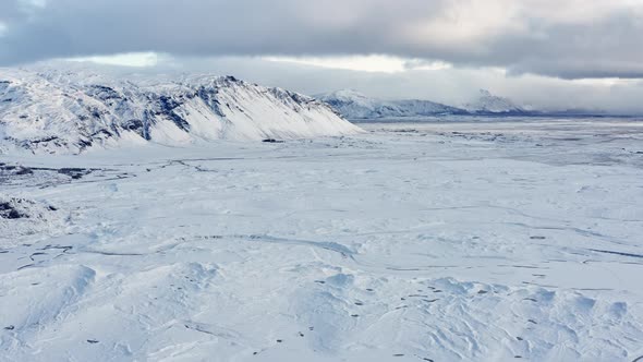 Drone Over Ice And Snowy Landscape With Mountains