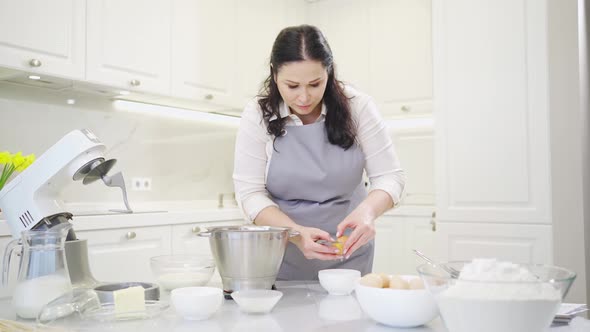 A Woman Breaks an Egg and Separates Yolks From Proteins