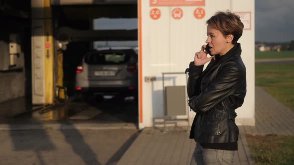 Attractive Girl Talking on the Phone in the Background of a Car Wash