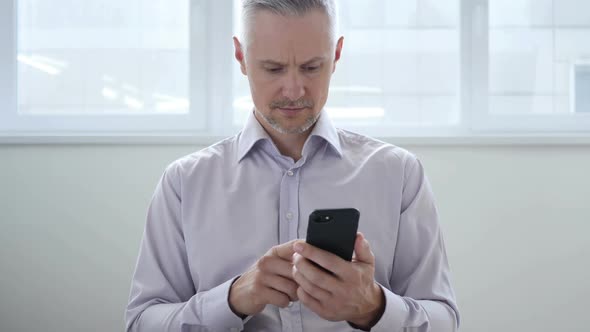 Middle Aged Man Browsing on Smartphone Using Internet