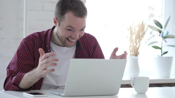 Excited Young Man Celebrating Success Working on Laptop