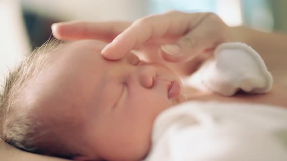 newborn baby close-up portrait lies mother's hand caressing the baby