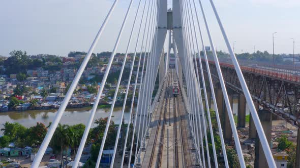 Metro train on Francisco del Rosario Sanchez bridge crossing river in Santo Domingo. Aerial view