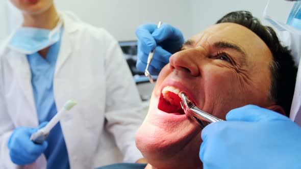 Dentists examining a male patient with tools