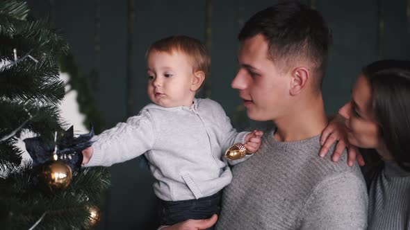 Parents with Little Son Looking at Cristmas Tree at Home