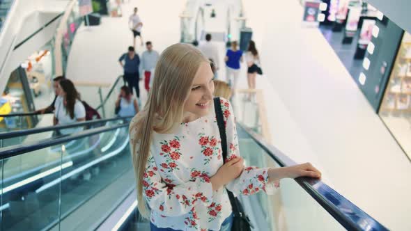 Young Blonde Woman Riding on Escalator. Amazed Woman in Shopping Center. Young Lady in Elegant
