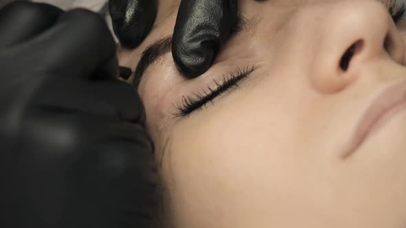 Microblading Procedure. Master Cosmetologist Draws and Notes with Eyebrow Pencil the Customer for