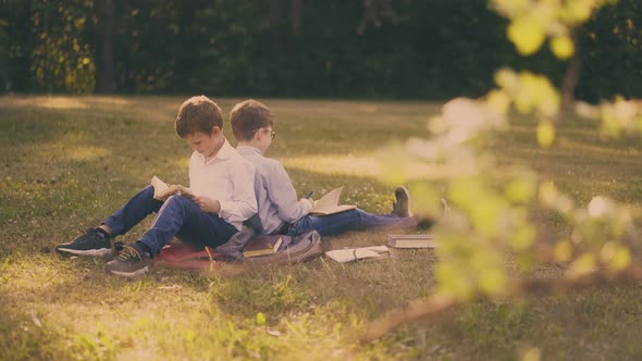 Cute Kids Prepare for School Test with Books Sitting in Park