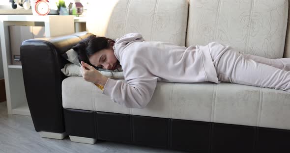 Drunk Young Woman Sleeping on Couch with Bottle