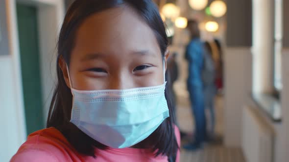 Asian Schoolgirl Wearing Protective Face Mask Taking Selfie at School Corridor