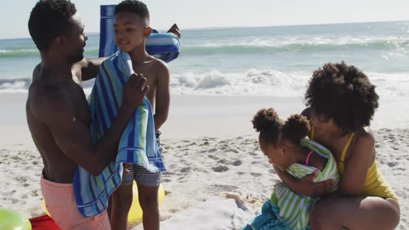 Smiling african american parents toweling off their children on sunny beach