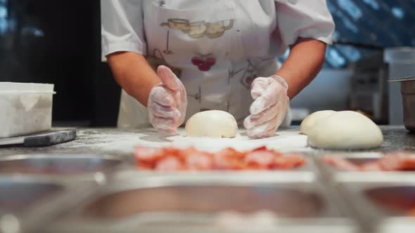 Cooking Pizza In A Pizzeria Restaurant, Chef Kneads And Rolls Out Pizza Dough Before Topping Filling