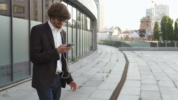 A successful and in a good mood businessman goes to his favorite job and listens to music