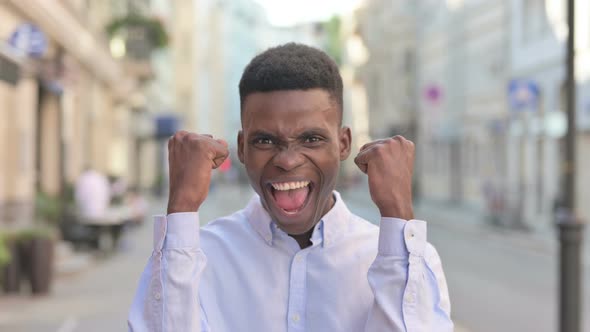 Portrait of Excited African Man Celebrating Success Outdoor