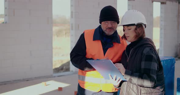 Concentrated Engineers Discussing Examining and Developing at Construction Site