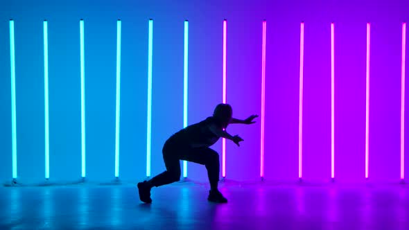 Young Woman Dancing Street Dance Hip Hop in a Studio with Neon Lighting Tube on a Blue Purple